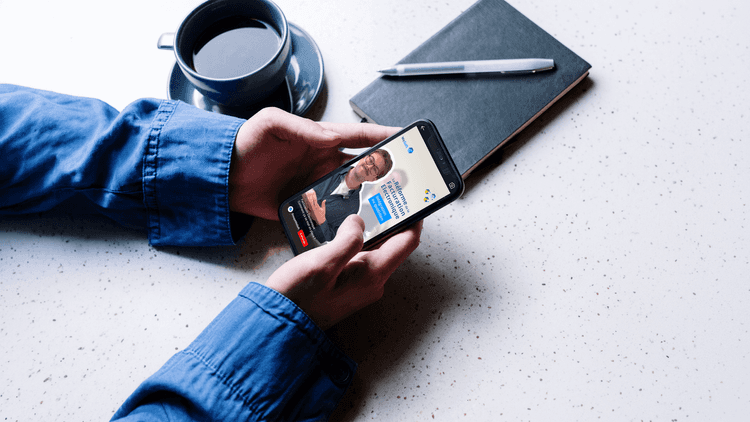 Mains qui tiennent un téléphone qui affiche la vidéo sur l'offre proposée par WeSoft dans le cadre de la RFE